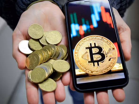 Coins beside a phone showing a trading chart